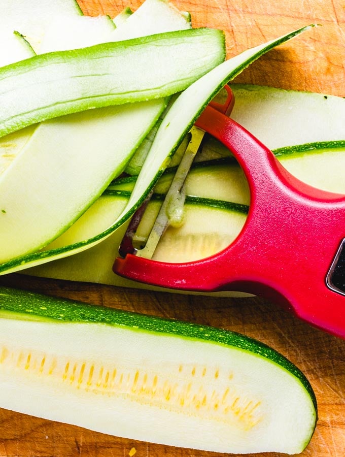 Vegetable peeler being used on the zucchini.