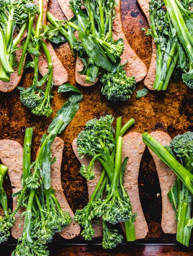 The sausage is topped with fresh broccolini.