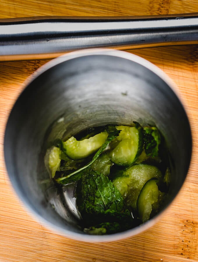 Muddling of cucumber, mint, and lime.