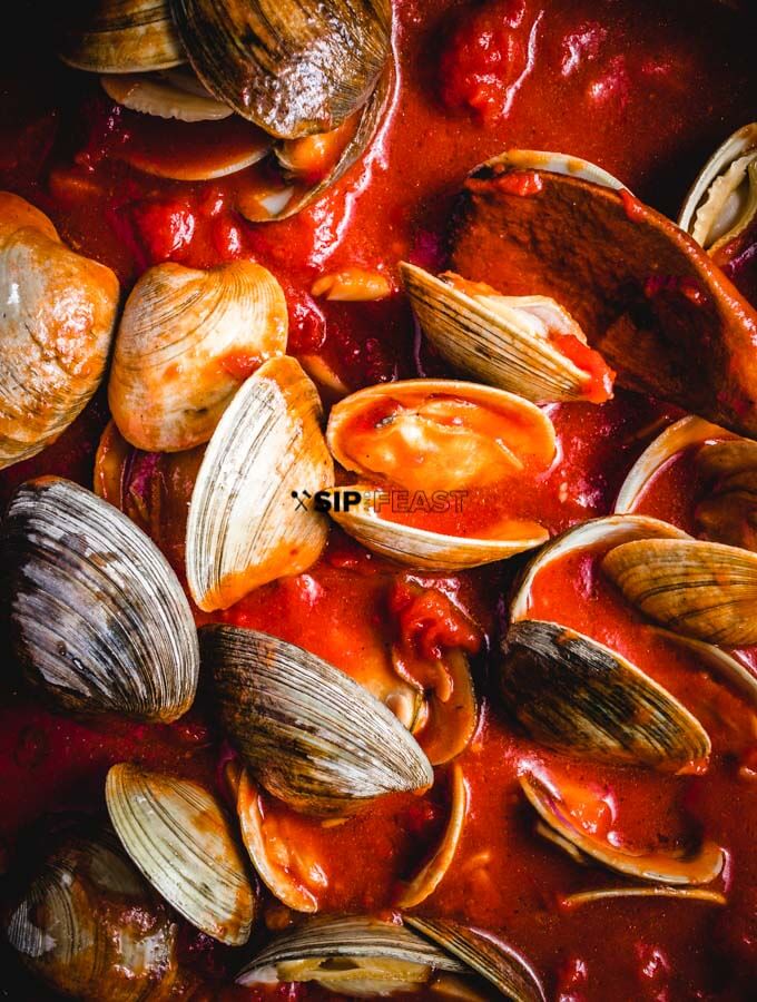 Clams In Red Sauce - sipandfeast.com #seafoodrecipe #dinner #italianfood #clams The clams added to the sauce.