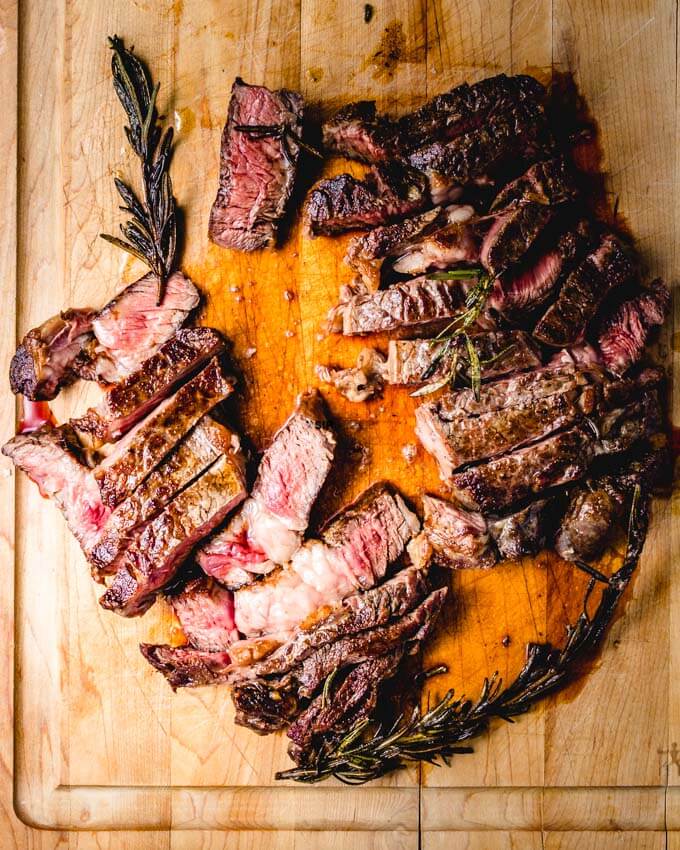 Rosemary ribeye sliced on cutting board.