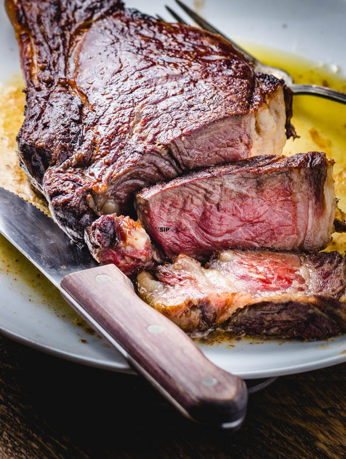 Ribeye steak cut up in plate with butter.