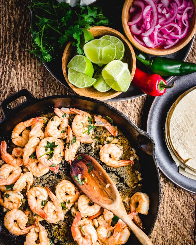 Shrimp taco recipe with limes, marinated red onions, tortillas, and cilantro.