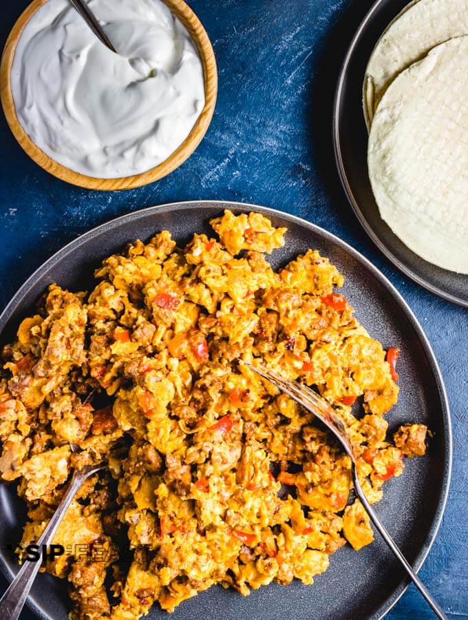 Plated Chorizo and eggs with sour cream and tortillas.