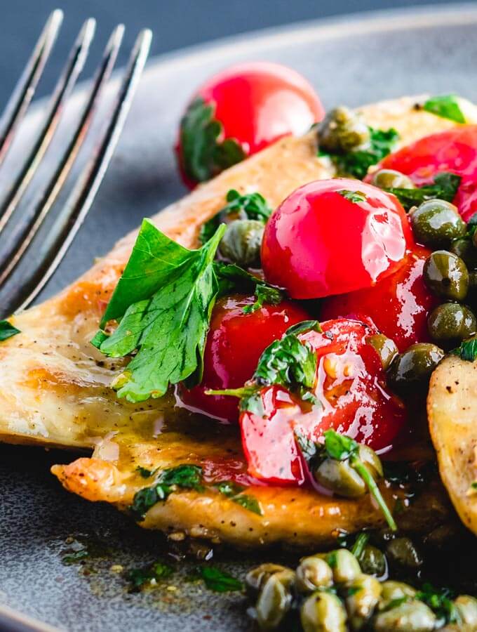  Italian chicken with capers and cherry tomato sauce closeup.