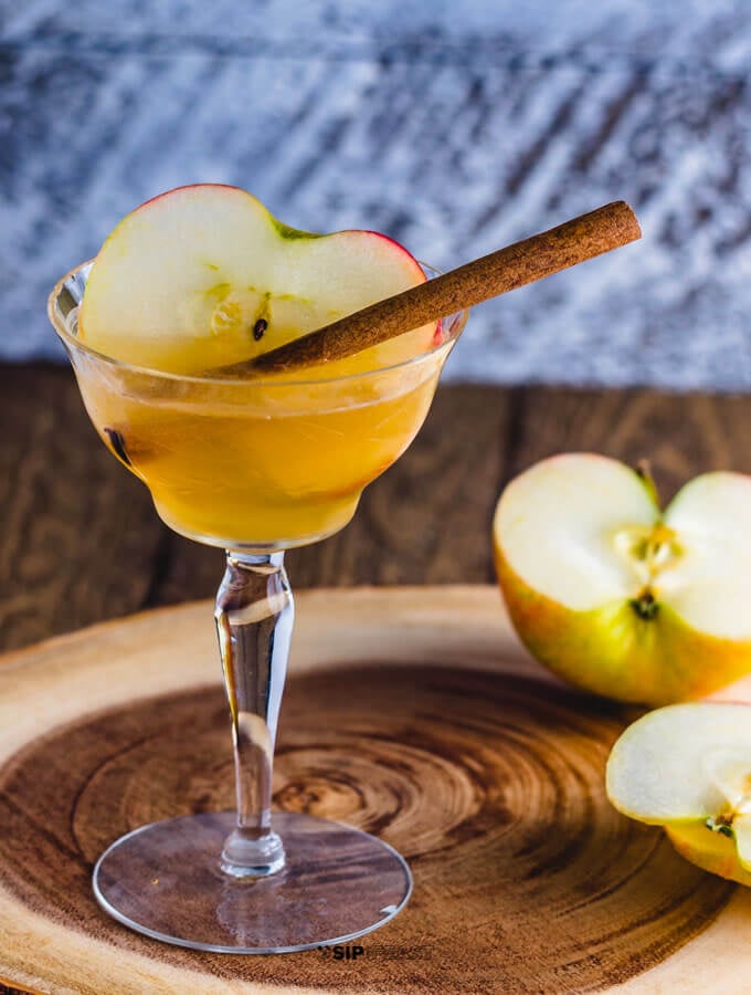 Apple cider cocktail with maple syrup and bourbon in a glass with apple and cinnamon.