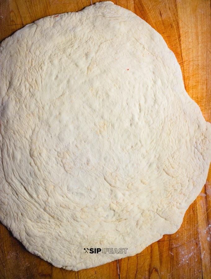 Rolled out pizza dough for the cheeseless pizza with heirloom tomatoes and fresh basil.