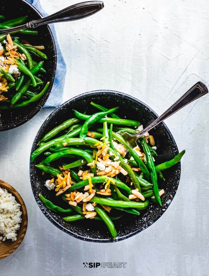 Green beans almondine with feta in 2 bowls.