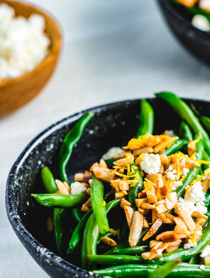 Green beans almondine with feta in serving bowl.