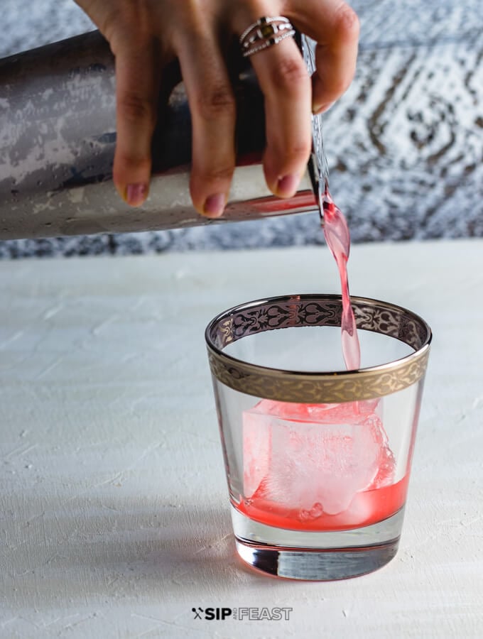 Grapefruit gin cocktail being poured into a glass from a cocktail shaker