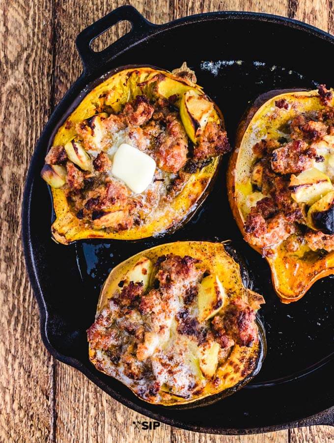 Finished sausage and apple stuffed acorn squash in cast iron pan.