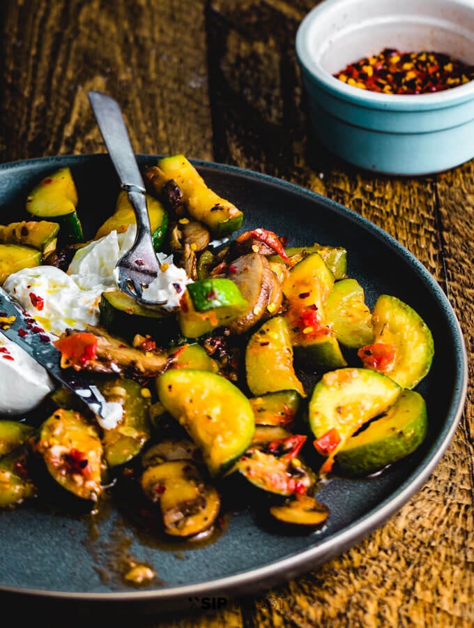 Zucchini and mushroom dish plated on table.