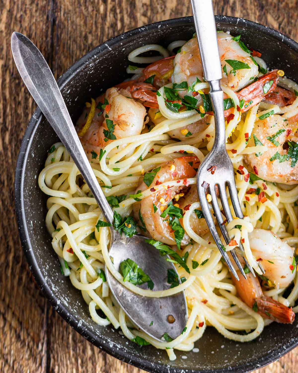 Lemon garlic shrimp pasta in black plate on table.