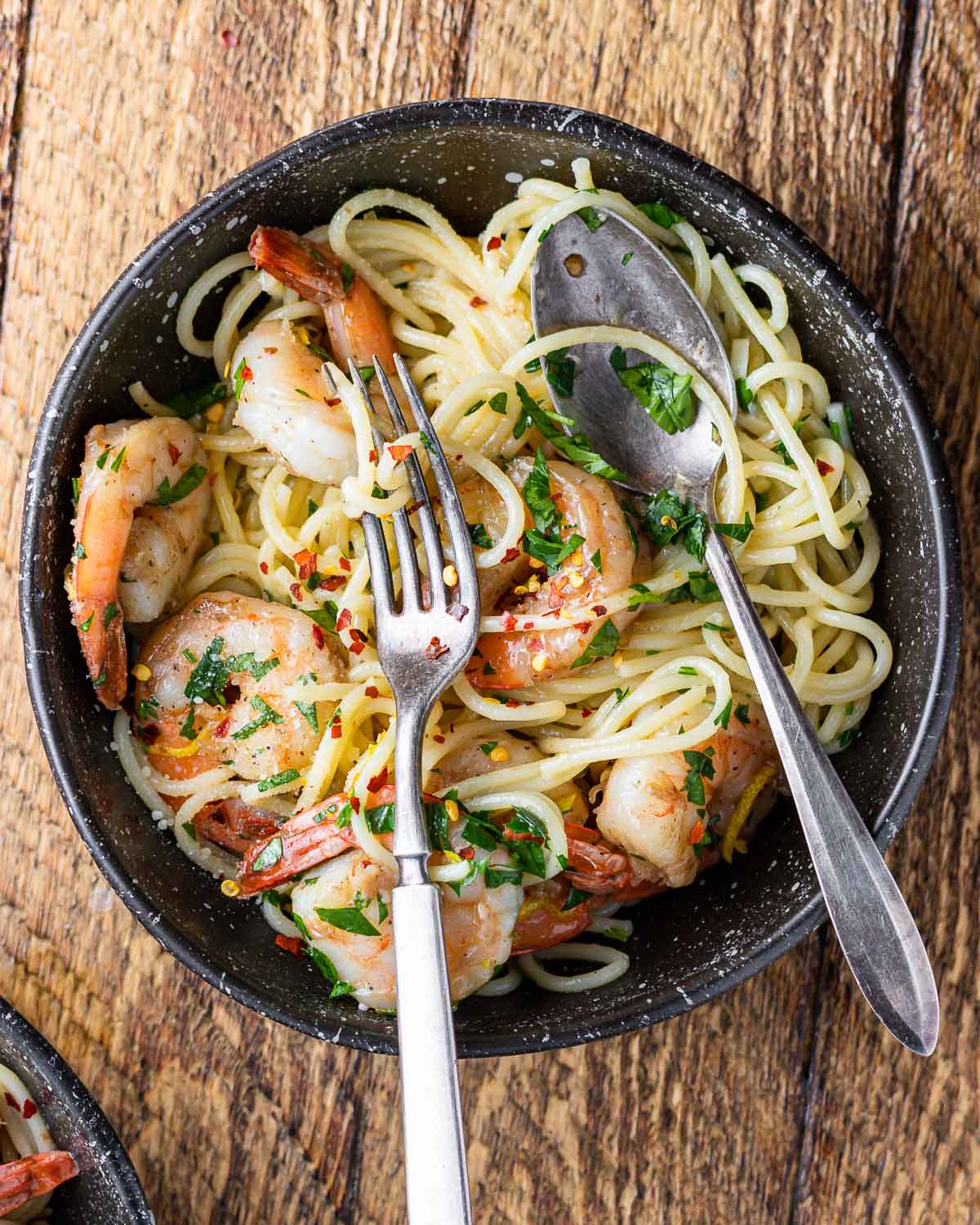 Lemon garlic shrimp pasta in black plate on wood table.