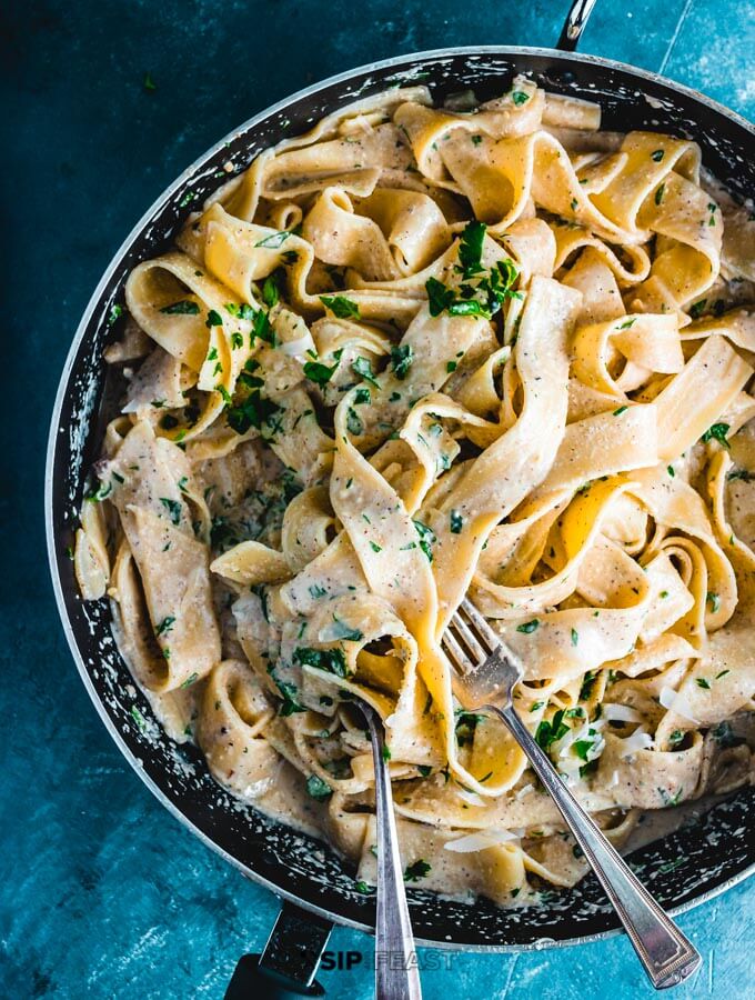 Walnut sauce mixed with pasta in pan.