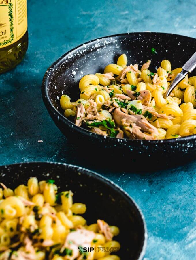 Tuna pasta in two plates with olive oil on side.