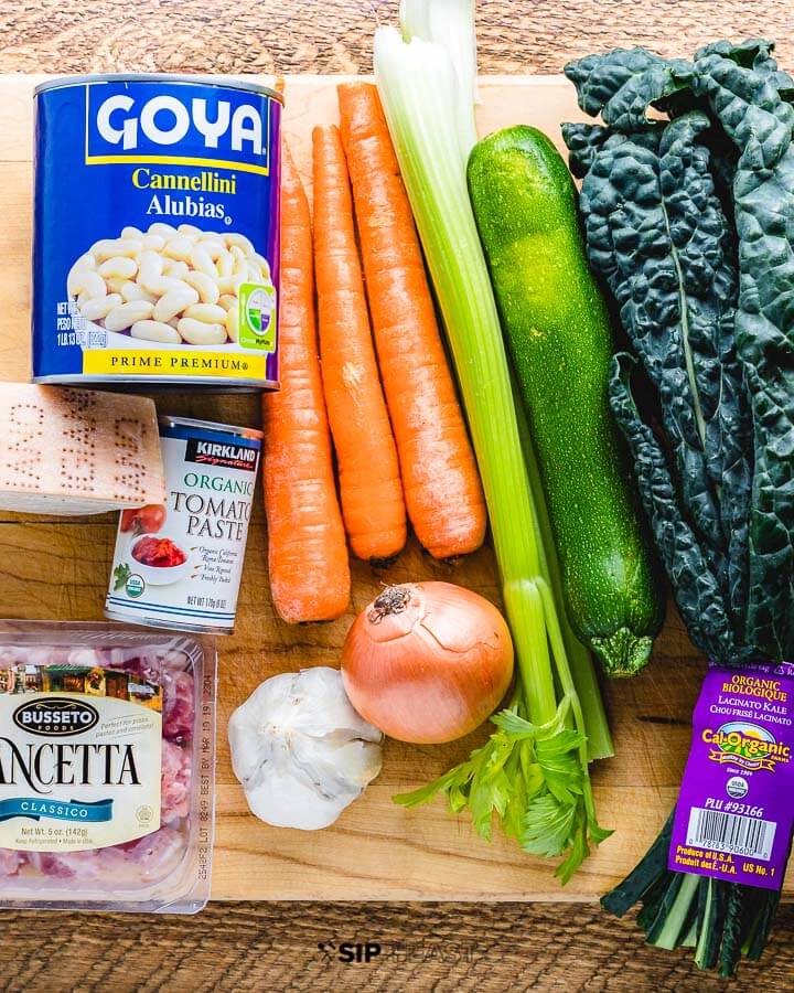 Tuscan soup ingredients shown: beans, pancetta, carrots, zucchini, kale, cheese, tomato paste, garlic and onion.