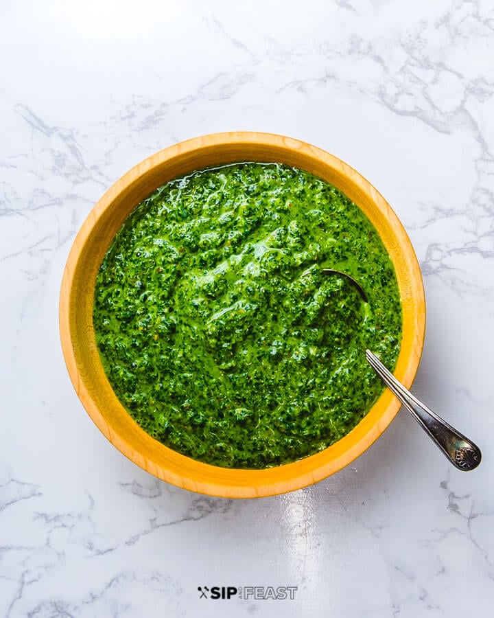 Italian green sauce in wooden bowl on white granite.