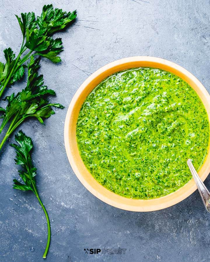 Italian salsa verde in wooden bowl on blue table.