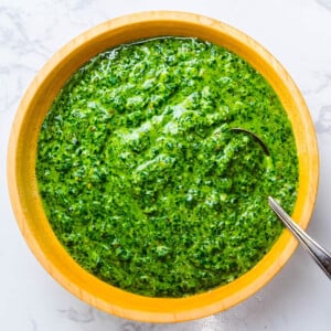 Italian salsa verde in wooden bowl on white granite.