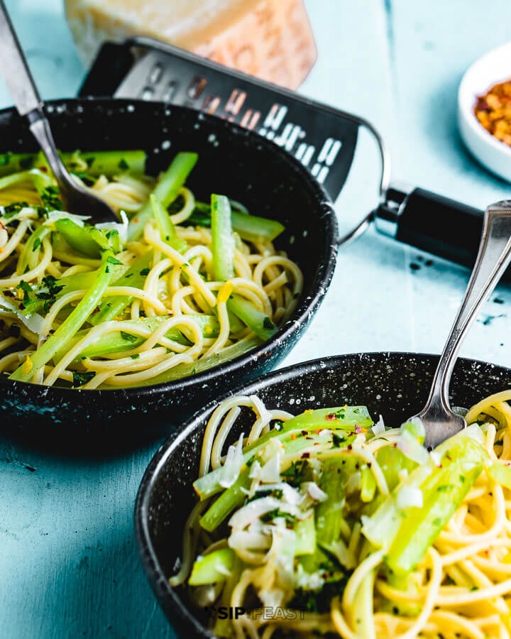 Two bowls of pasta on blue table.