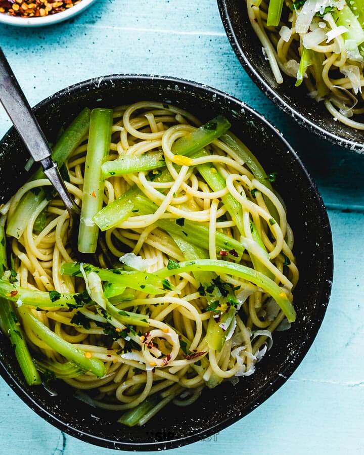 Overhead photo of celery pasta in a bowl on blue table.