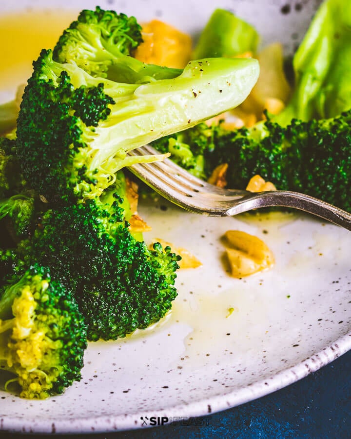 Closeup shot of broccoli floret held by fork.
