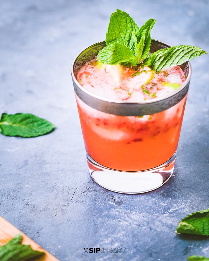 Strawberry mojito in a glass with mint leaves on blue table.