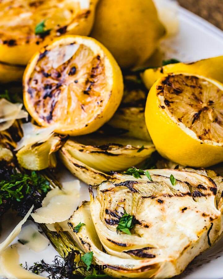 Close up shot of grilled lemons and fennel in white plate.