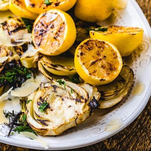 Grilled fennel and grilled lemons on white plate.