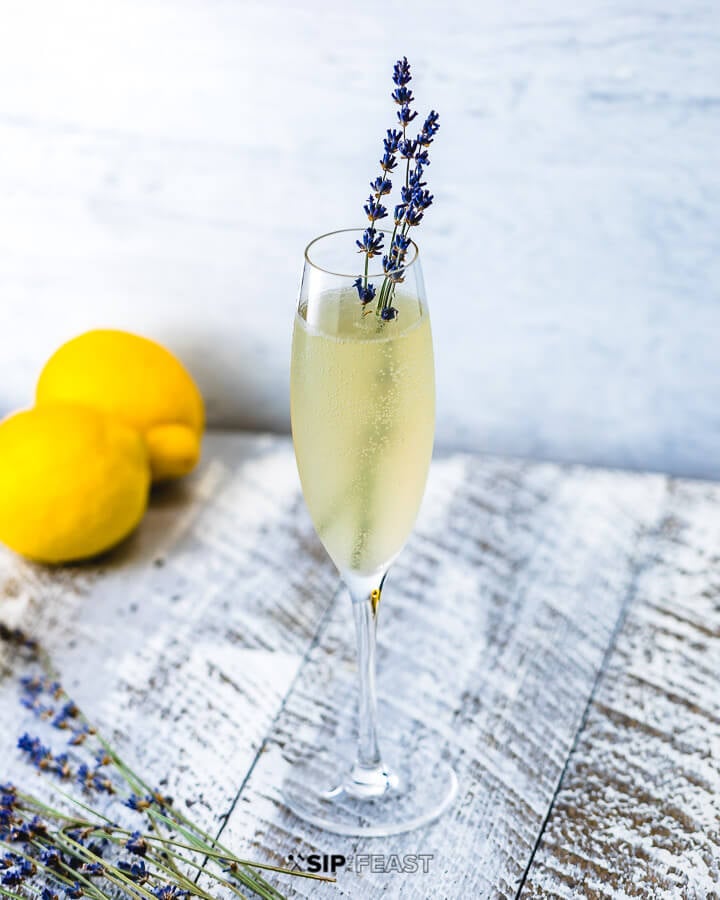 Champagne flute with lavender french 75, fresh lavender and lemons.