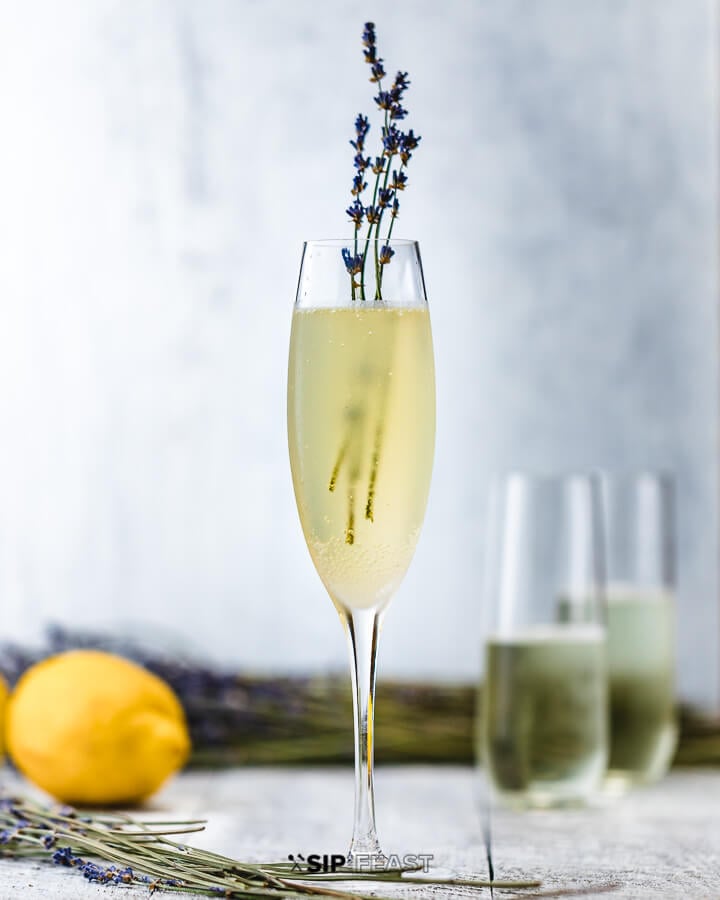 Glass of french 75 with lavender and lemons in the background.