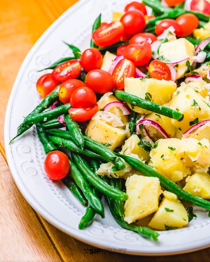 Italian potato green bean salad in platter on wood table.