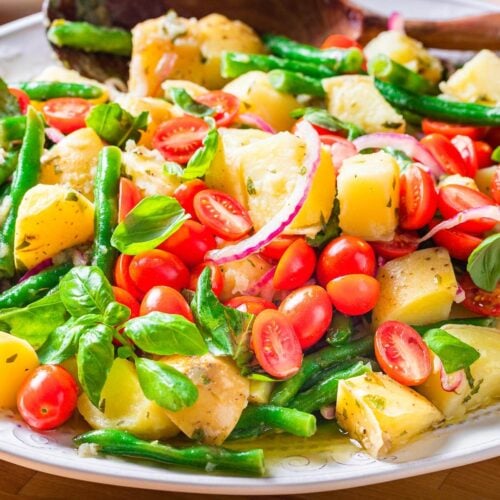 Italian green bean potato salad in platter on blue table.