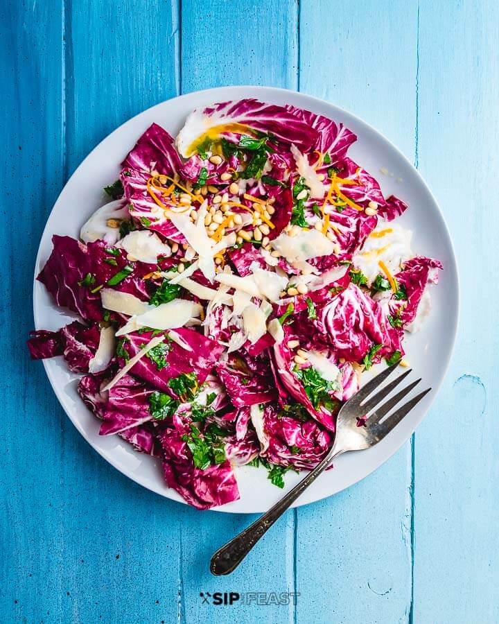 Radicchio salad in serving platter on blue table.