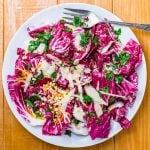 Radicchio salad in white serving dish on wood table.