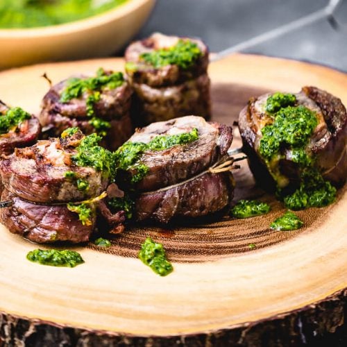 Steak pinwheels on cutting board topped with green sauce.