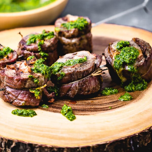 Steak pinwheels on cutting board topped with green sauce.