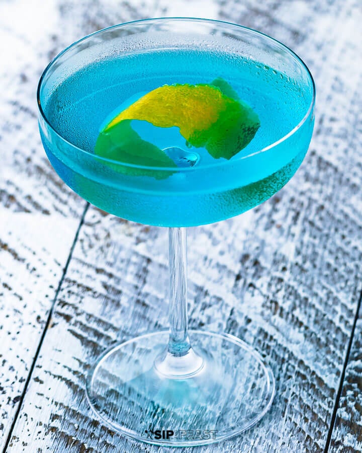 Coupe glass with angelo azzurro cocktail and lemon peel.