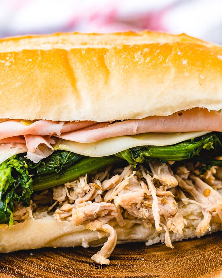 Closeup shot of shredded pork sub with broccoli rabe, provolone and mortadella.