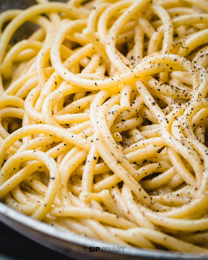 Cacio e pepe în tigaie cu piper presărat.