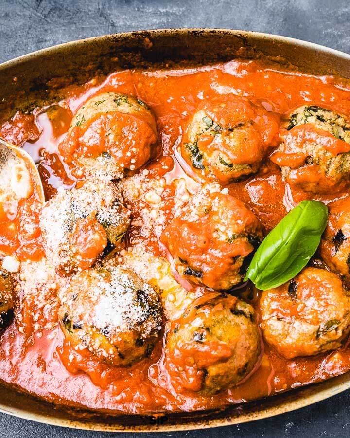 Eggplant meatballs in pan on blue background.