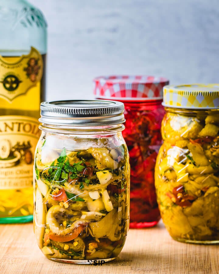 Italian Pickled Eggplant - sipandfeast.com #pickledeggplant #eggplant #italianrecipes Three jars of Italian pickled eggplant on cutting board.