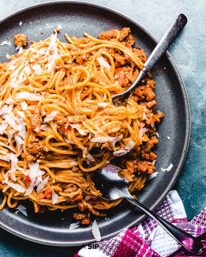 Spaghetti Bolognese in grey plate on blue background.