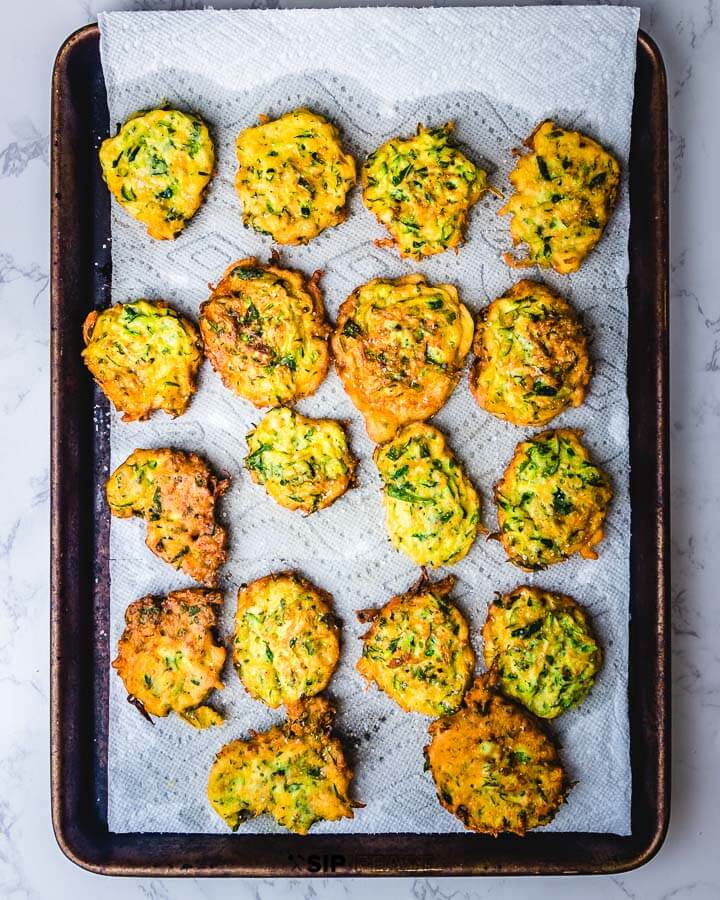 Sheet pan of fritters on paper towels.