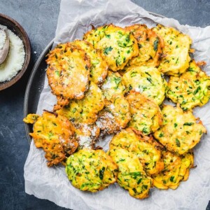 Italian zucchini fritters on parchment paper lined plate.