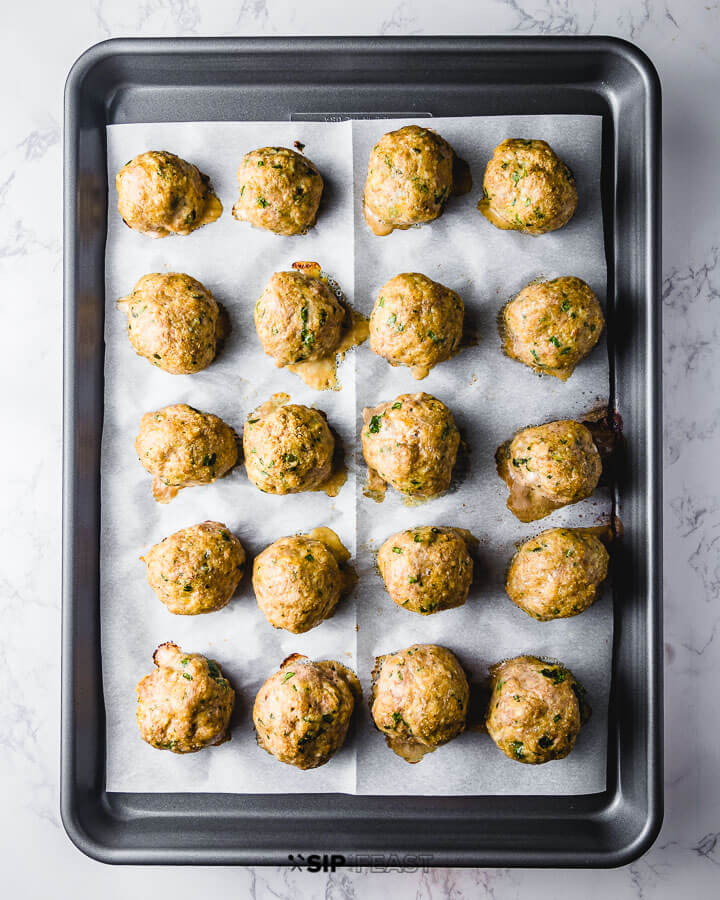 Fully cooked meatballs on parchment paper lined pan.