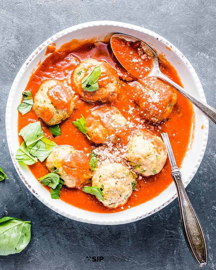 Turkey meatballs with red sauce in white bowl.