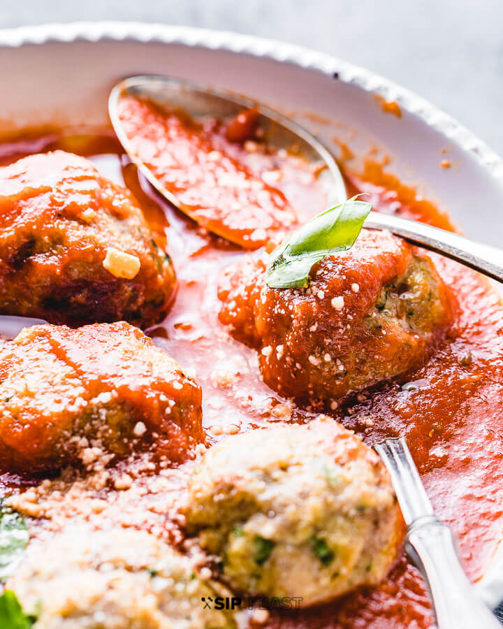 Turkey meatballs with red sauce in a white bowl.