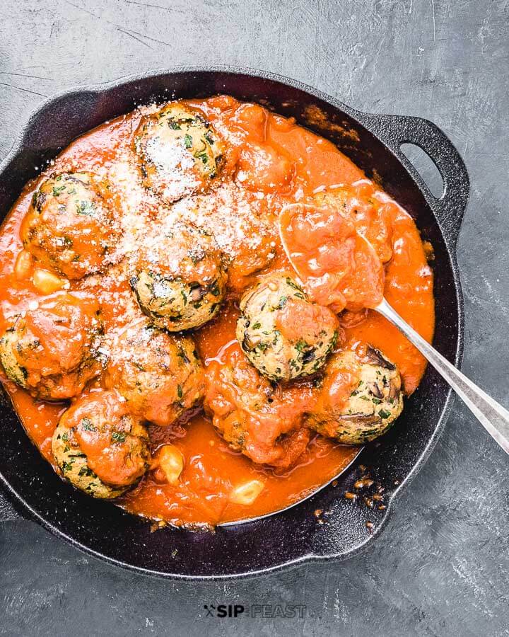 Mushroom meatballs in cast iron pan on blue background.